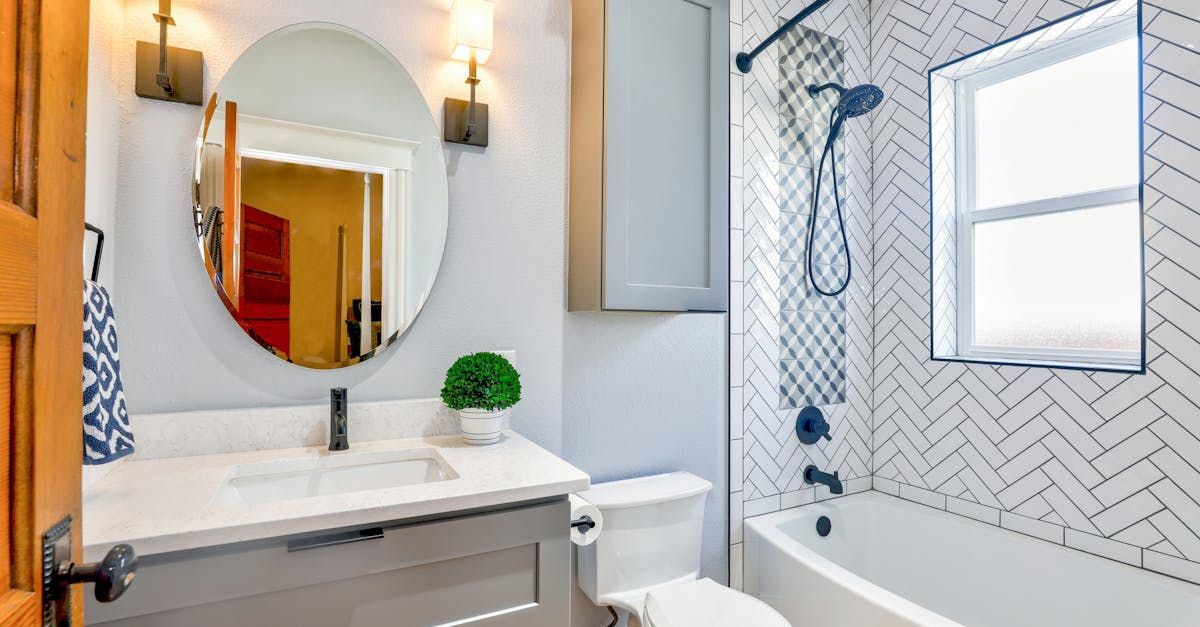 A bathroom with a sink , toilet , shower and mirror.