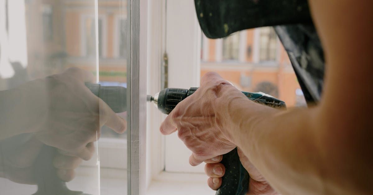 A man is using a drill to fix a window.