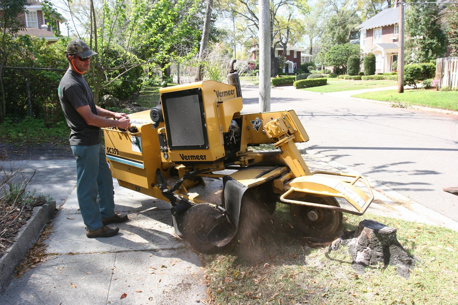 A man is standing next to a yellow vanguard stump grinder