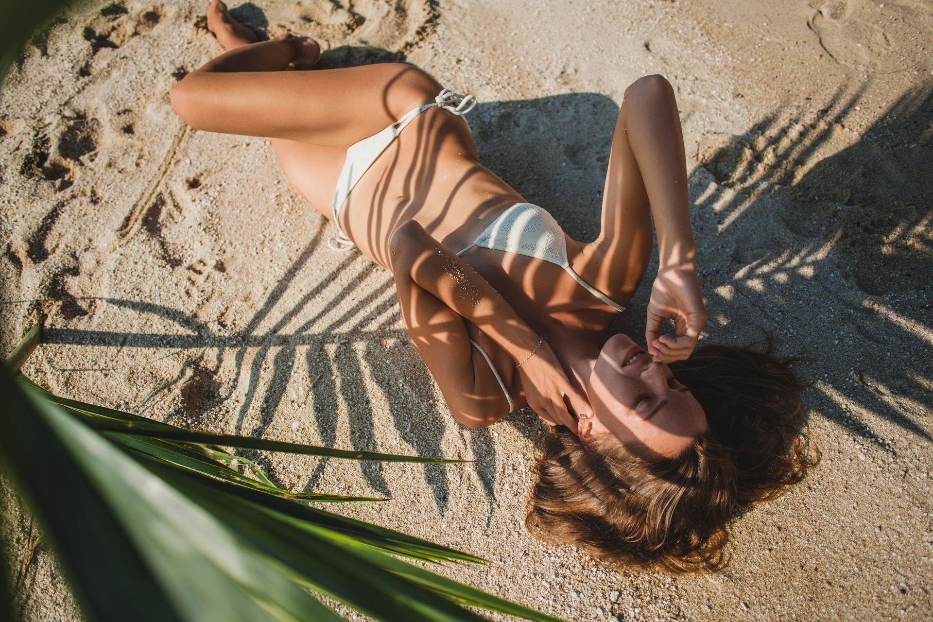 Mulher tomando sol na praia embaixo do coqueiro