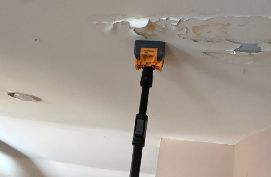 Ceiling with peeling paint, being cleaned with a vacuum attachment.