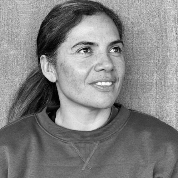 Woman with dark hair in a sweatshirt, looking slightly off-camera with a subtle smile.