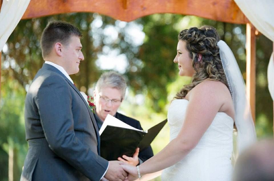 A bride and groom are holding hands during their wedding ceremony.