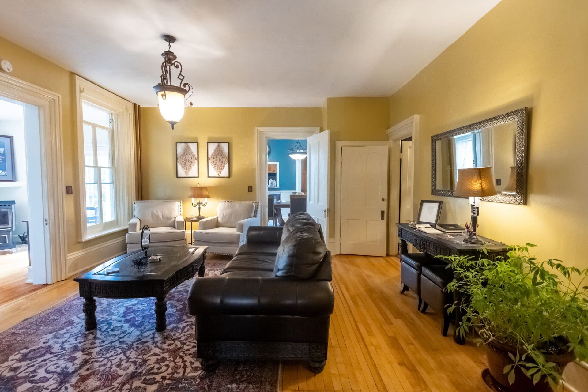 A living room with a couch , two chairs , a coffee table and a mirror.