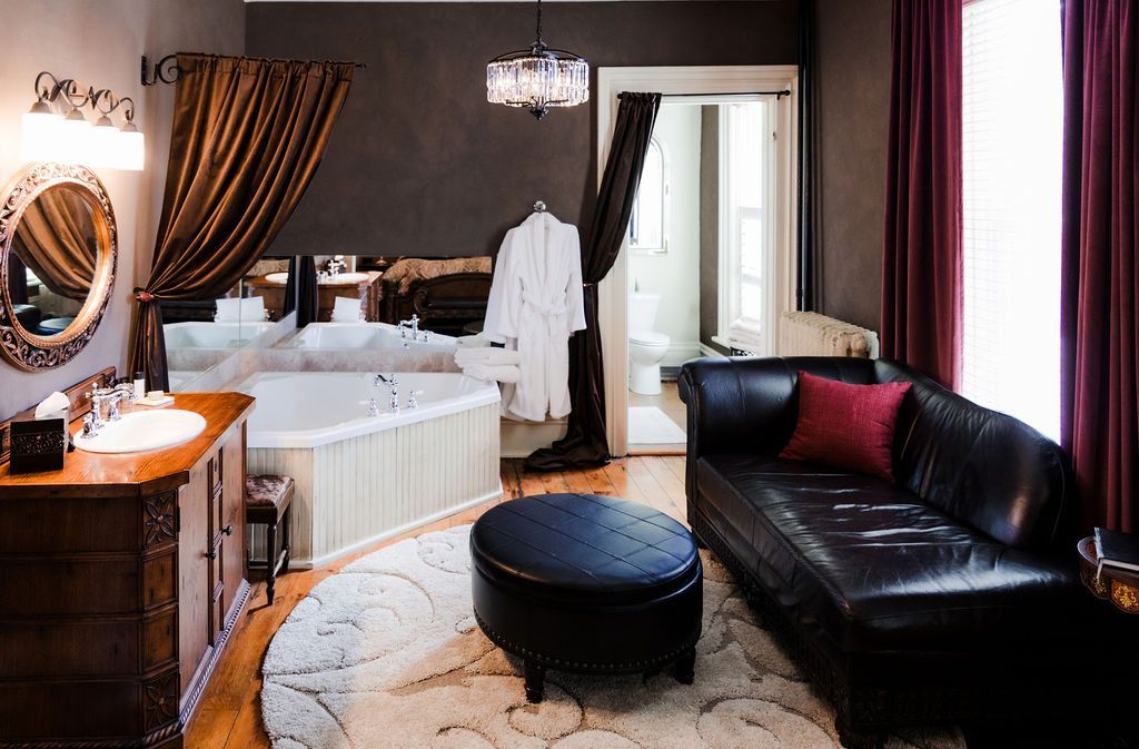 Luxurious hotel room with a jacuzzi, leather sofa, and decorative curtains.