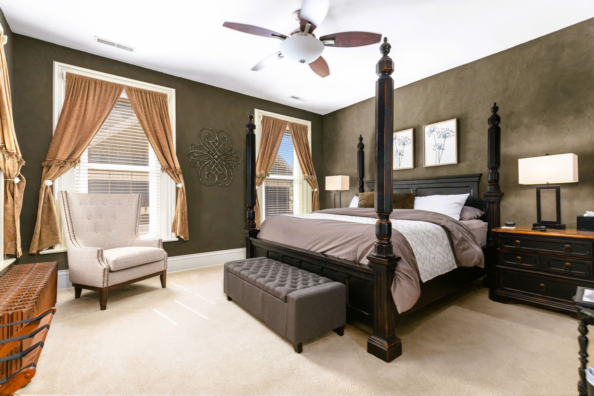 Bedroom with dark brown walls, a four-poster bed, armchair, and brown curtains.