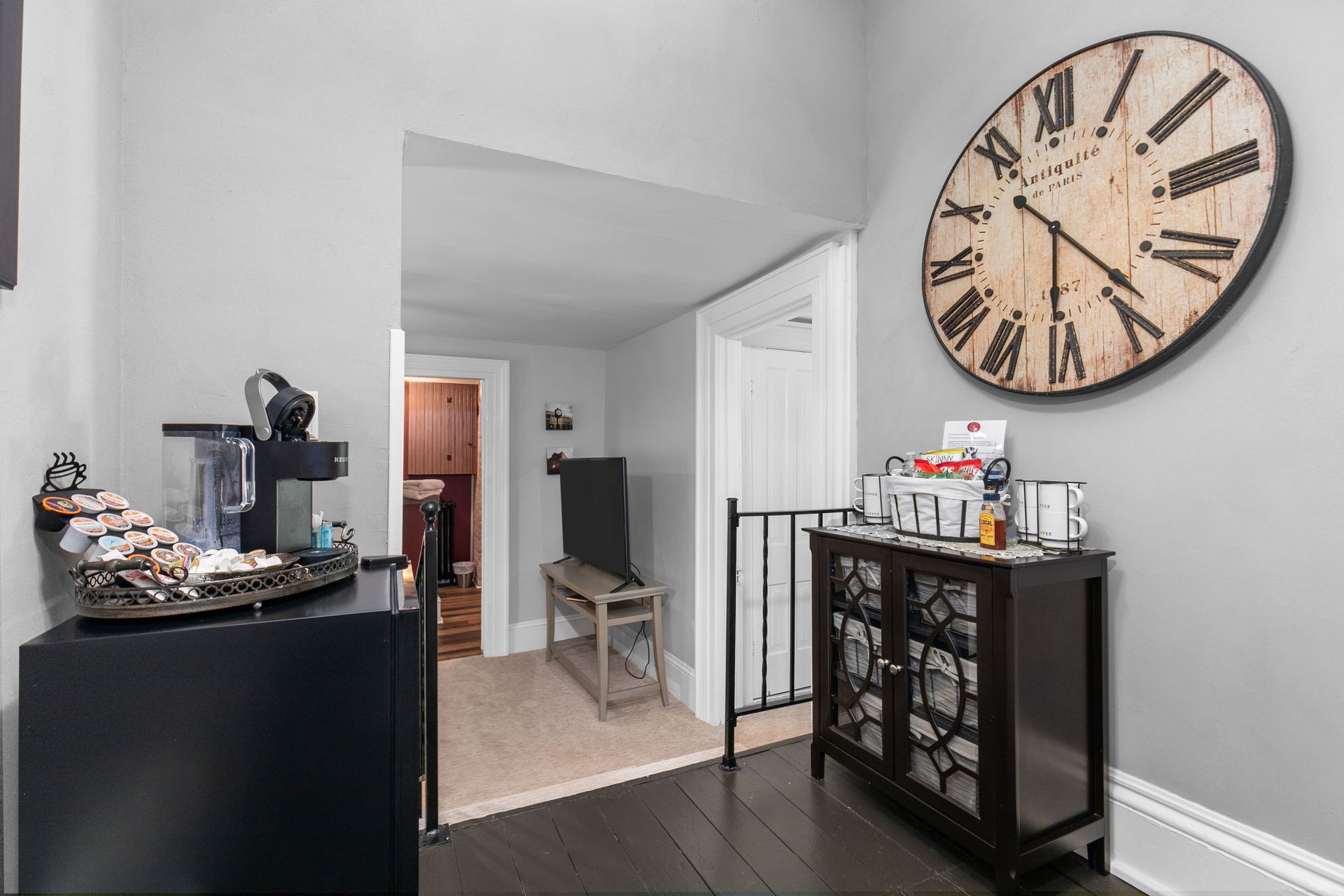 Entryway with clock, cabinet, and doorway; black floor and gray walls.