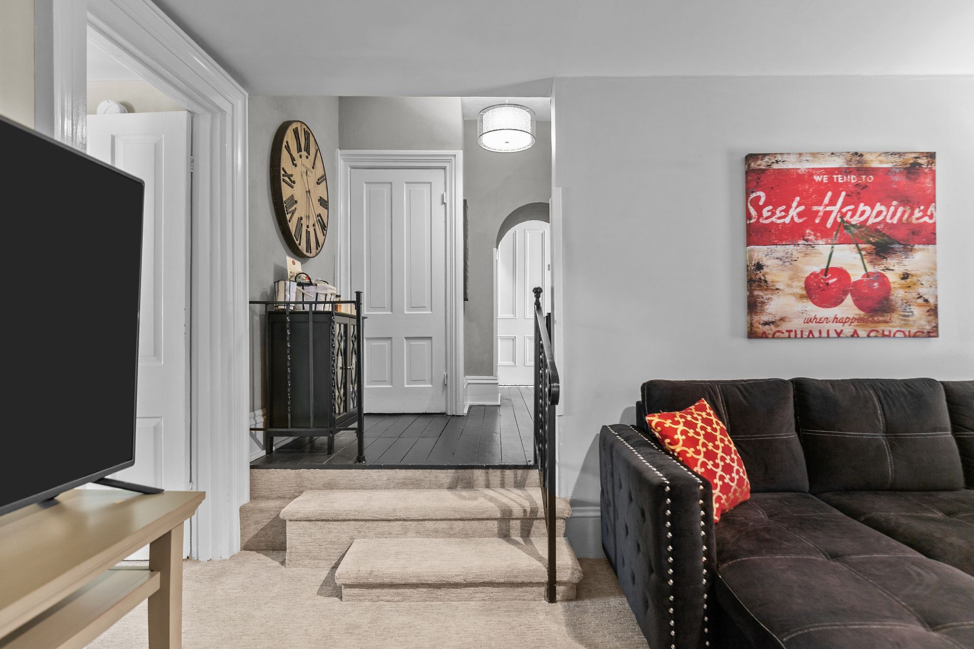 Living room with a sectional sofa, artwork, and a set of stairs leading to other rooms.