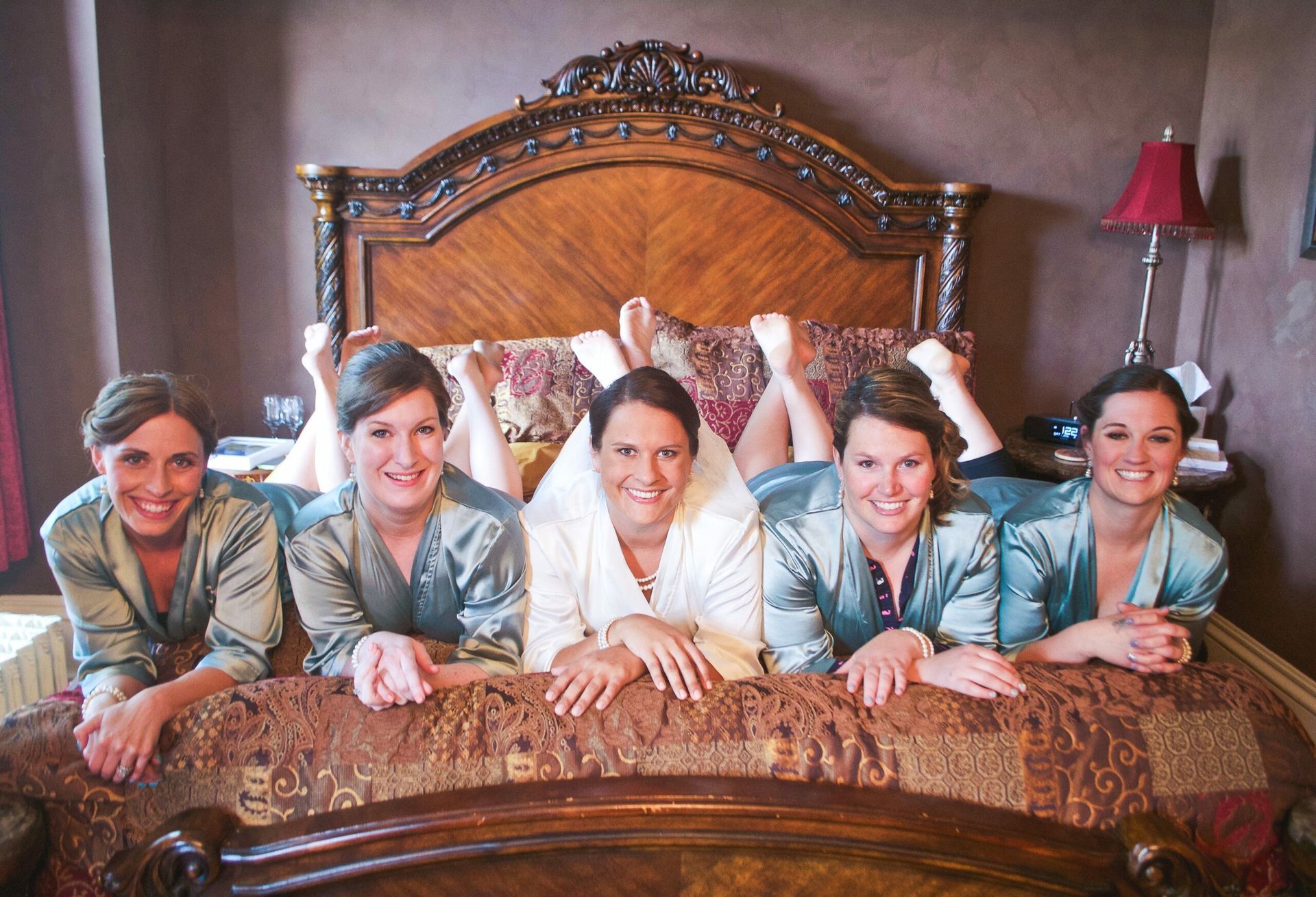 A bride and her bridesmaids are posing for a picture on a bed