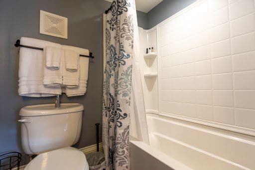 A bathroom with a toilet , bathtub and shower curtain.
