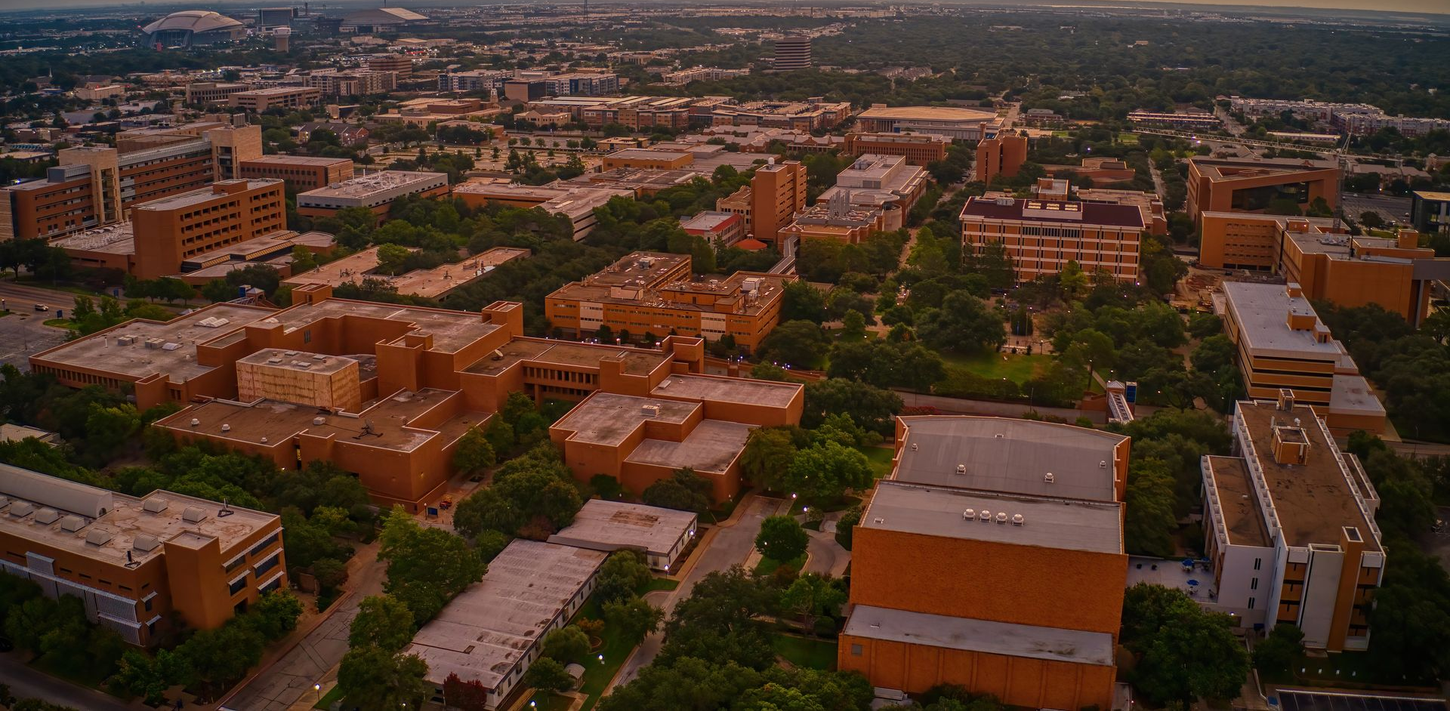 Aerial view of a city campus, with multiple brick buildings and trees.