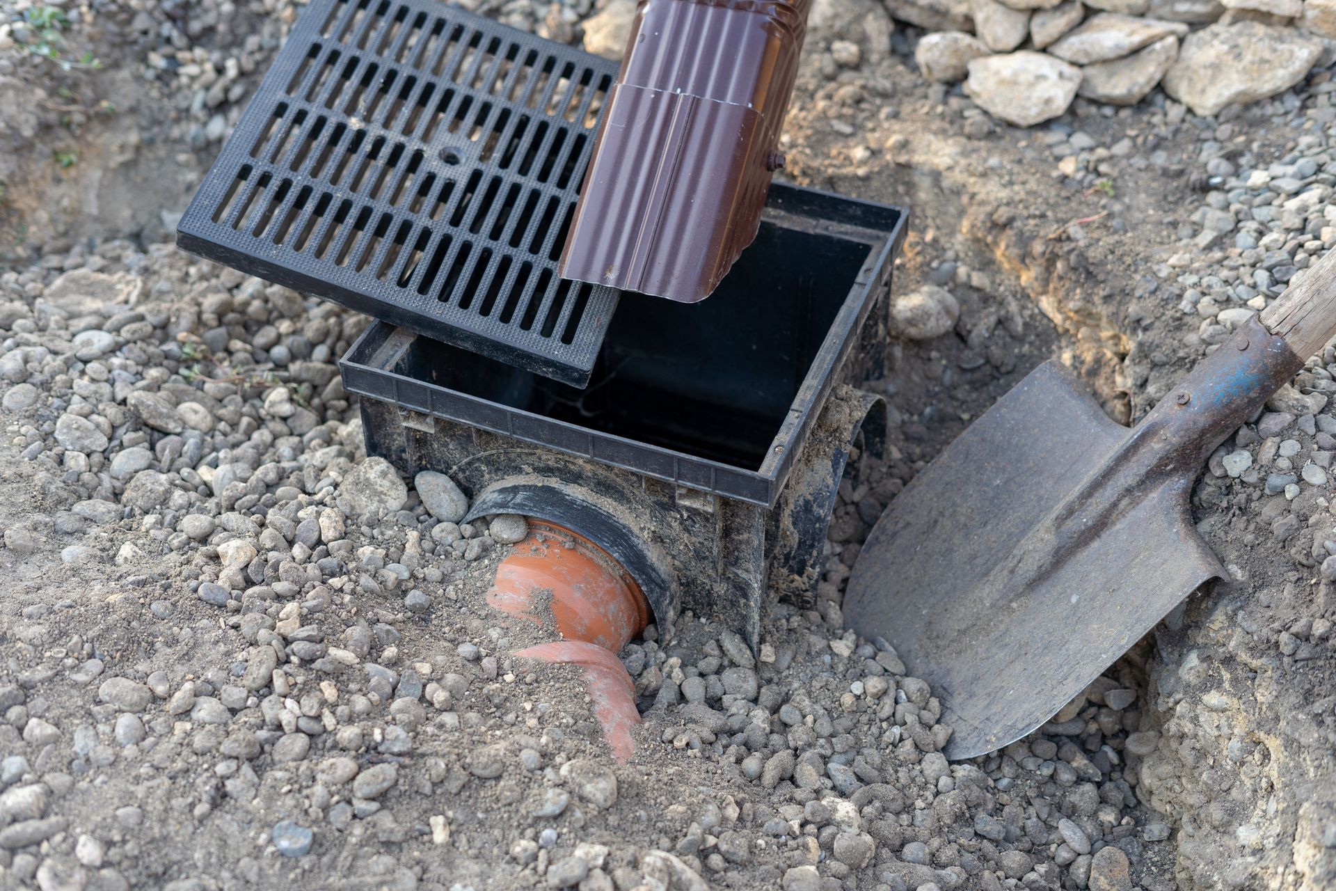 Workers installing a sewage and rainwater drainage system in a construction site trench.