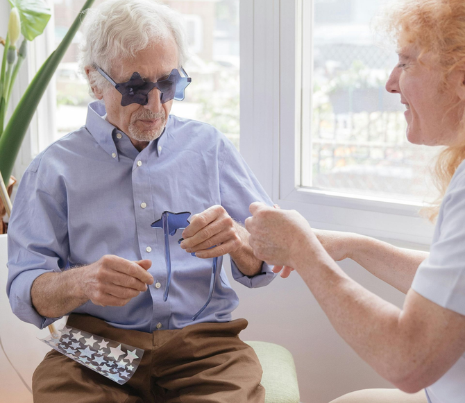 Two people in a bright room exchanging an eyeglass frame and cleaning cloth