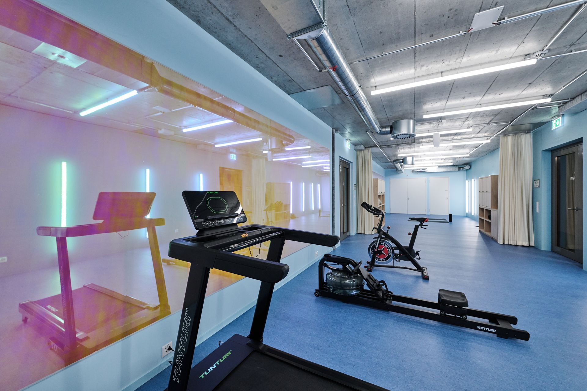 In einem Fitnessstudio gibt es ein Laufband und ein Rudergerät.