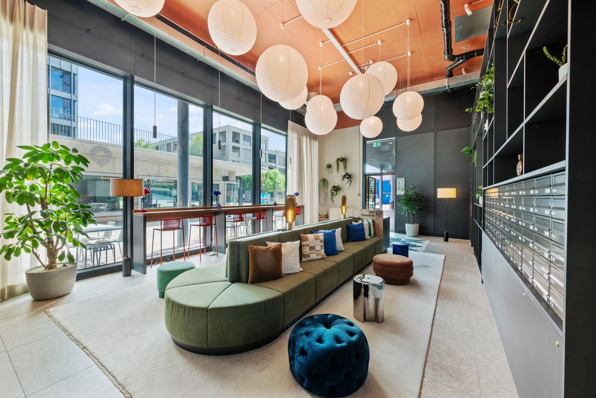 A living room with a couch , ottomans , and a lot of windows.