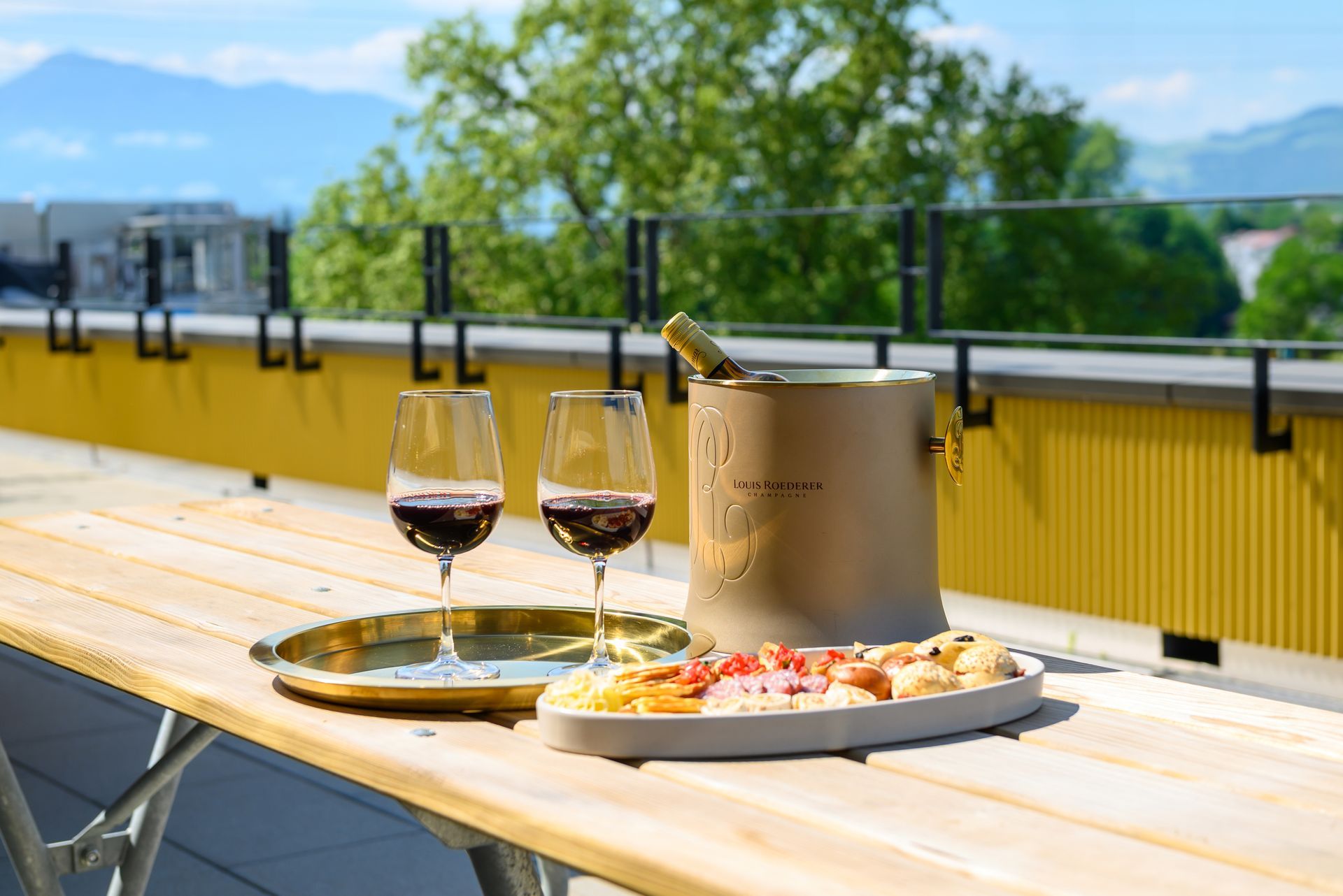 Two glasses of wine and a bucket of champagne are on a wooden table.