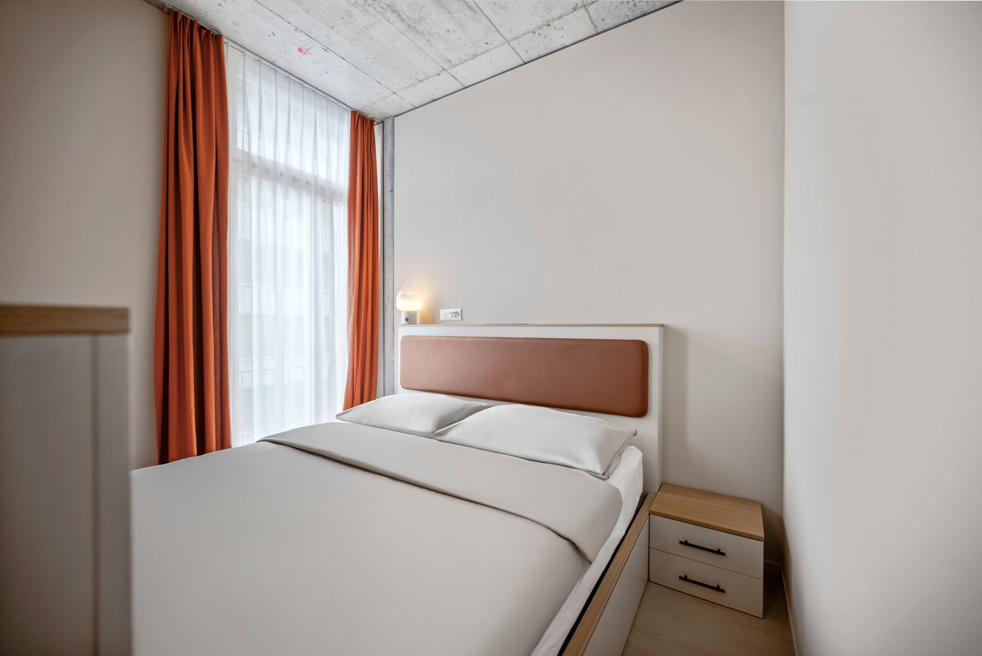 Ein Schlafzimmer mit Bett, Nachttisch und Fenster.