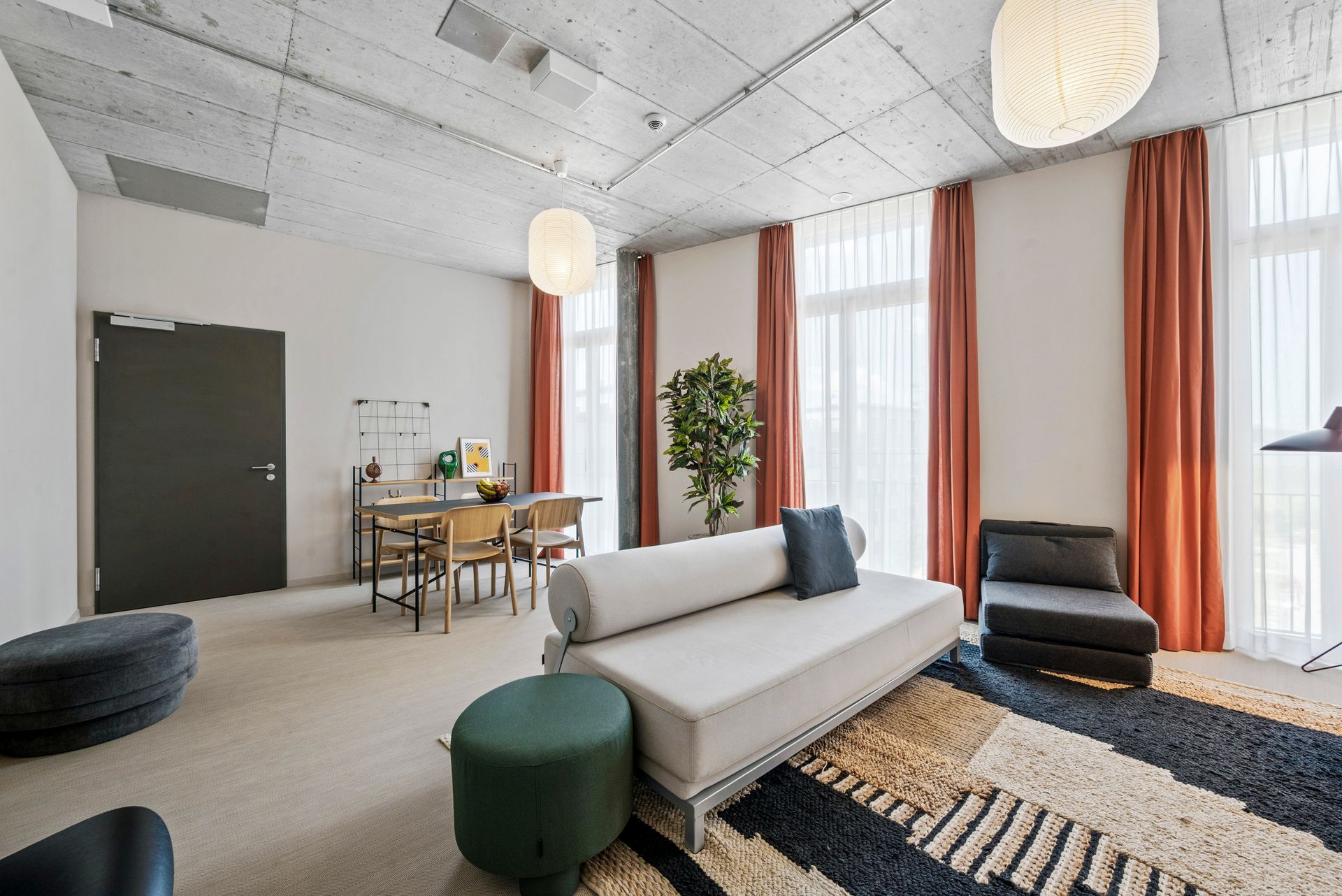 Ein Wohnzimmer mit einem Sofa, Stühlen, Ottomanen und einem Teppich.