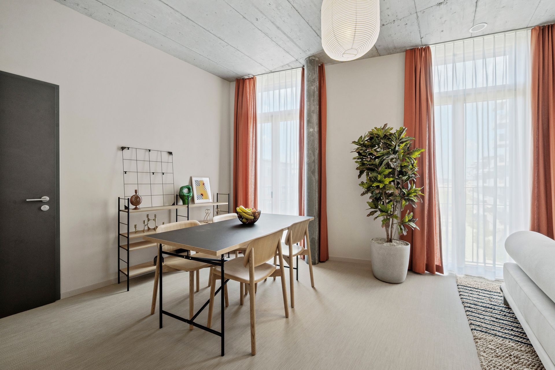 Ein Wohnzimmer mit einem Tisch und Stühlen und einer Topfpflanze.