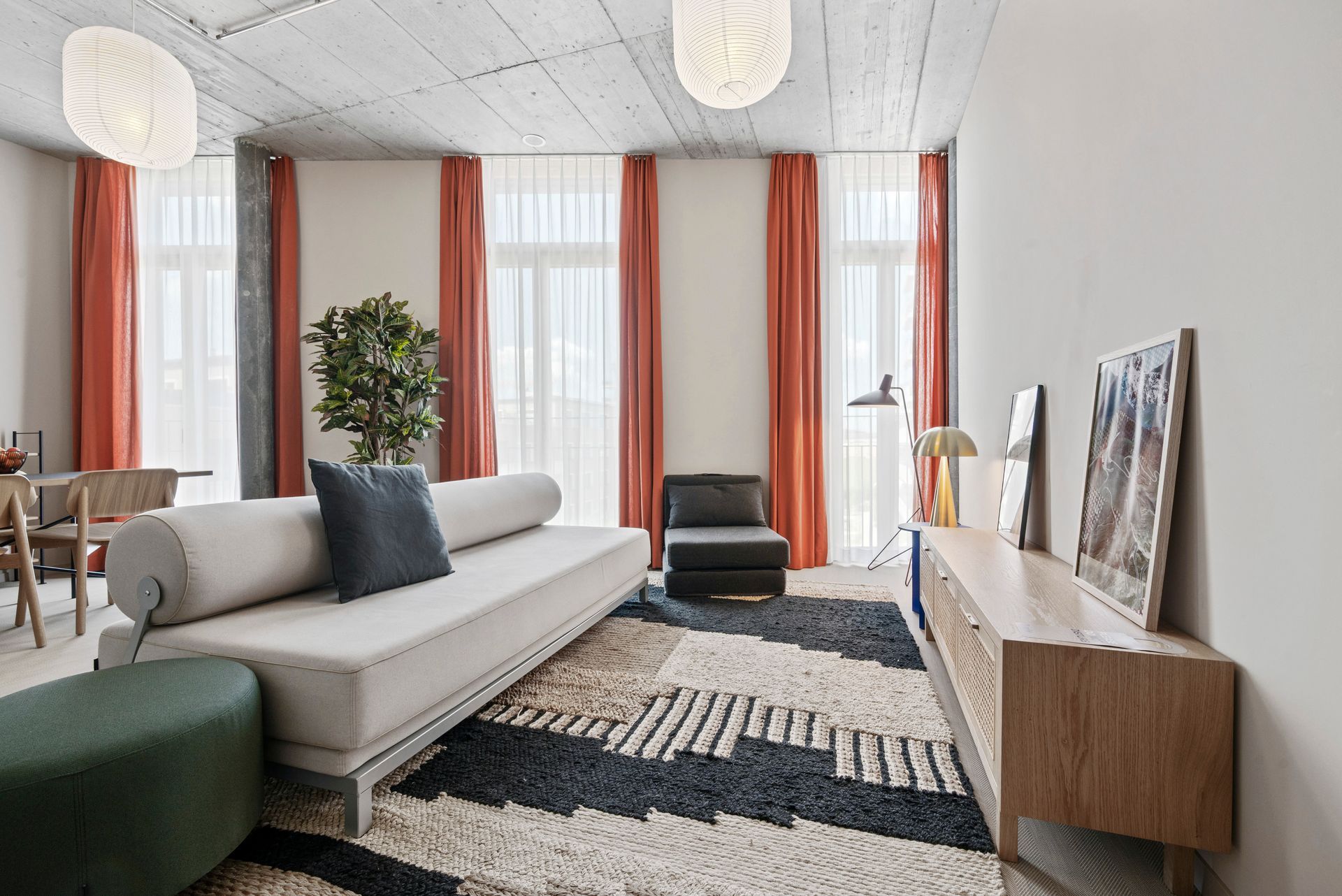 Ein Wohnzimmer mit Couch, Sessel, Teppich und Fernseher.