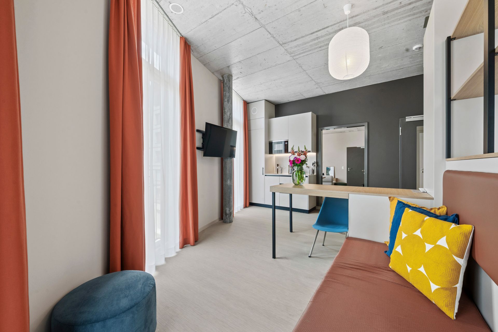 A living room with a couch , desk , chair and television.