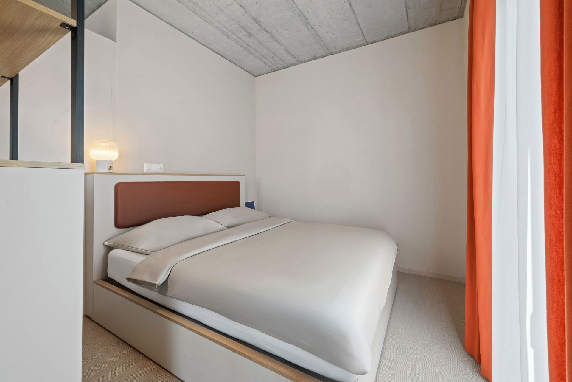 Ein Schlafzimmer mit einem Bett und einem Fenster mit orangefarbenen Vorhängen.