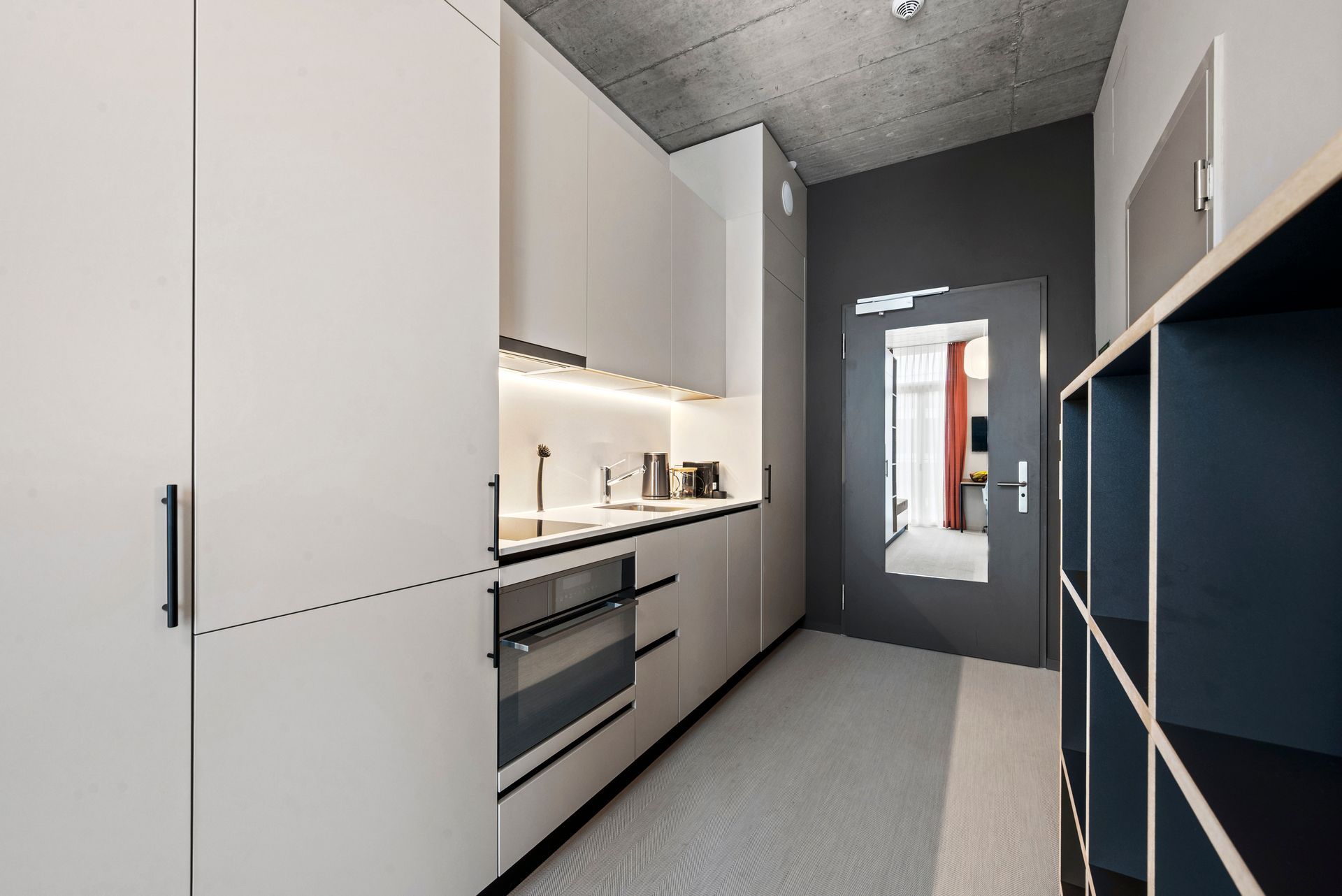 A kitchen with white cabinets , a stove , a refrigerator and a mirror.