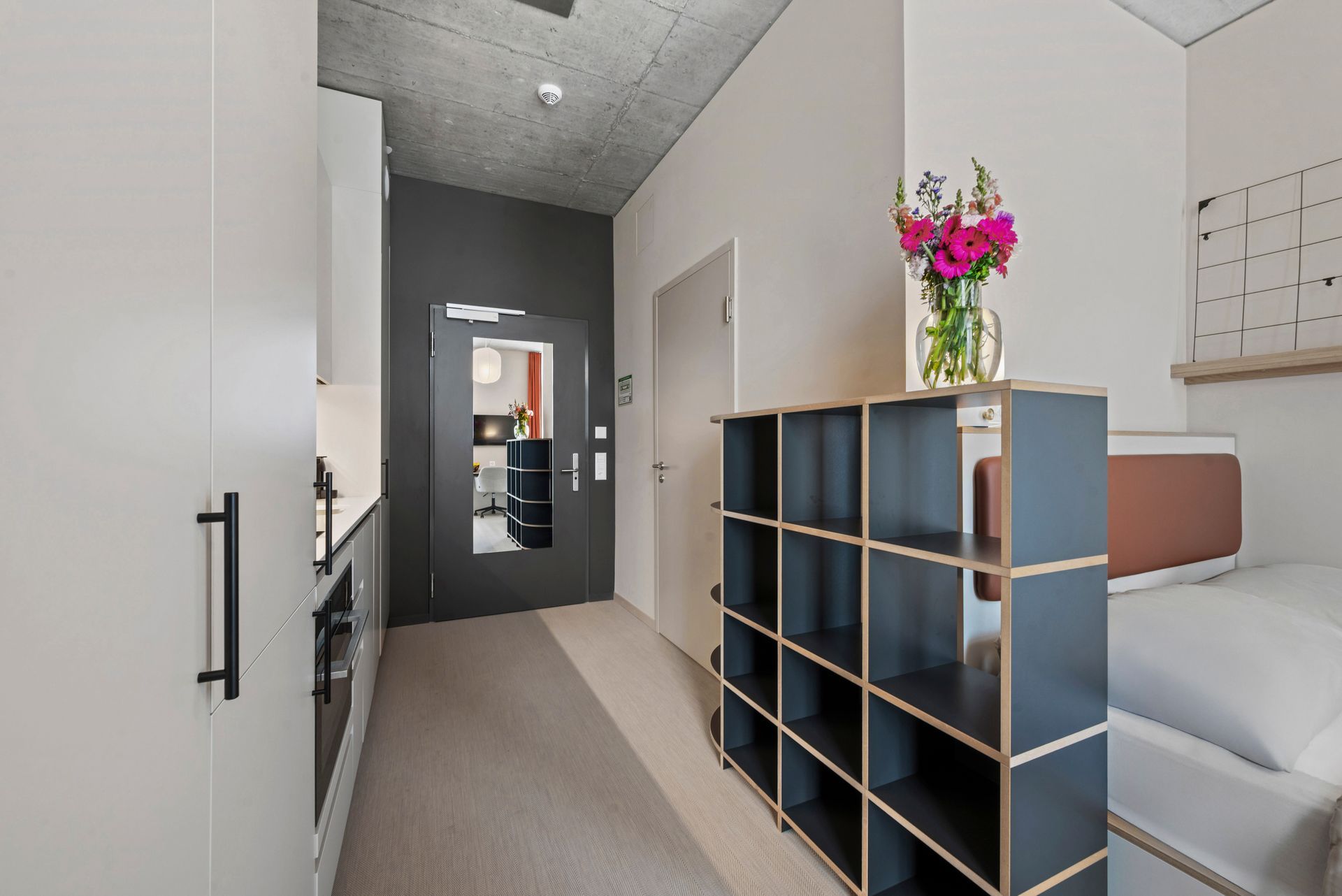 Ein Zimmer mit einem Bett und einem Regal mit Blumen darauf