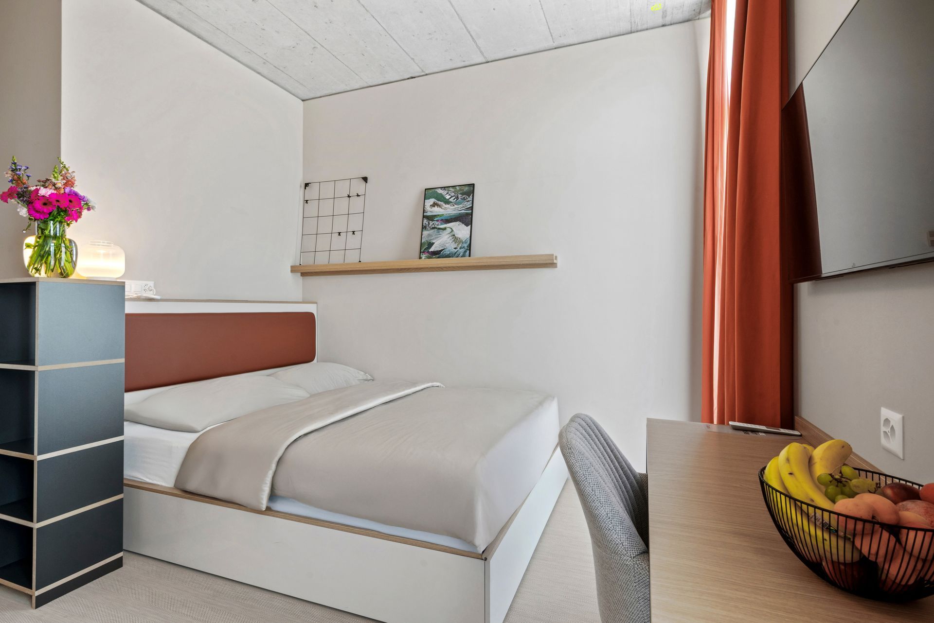 Ein Hotelzimmer mit Bett, Schreibtisch und Fernseher