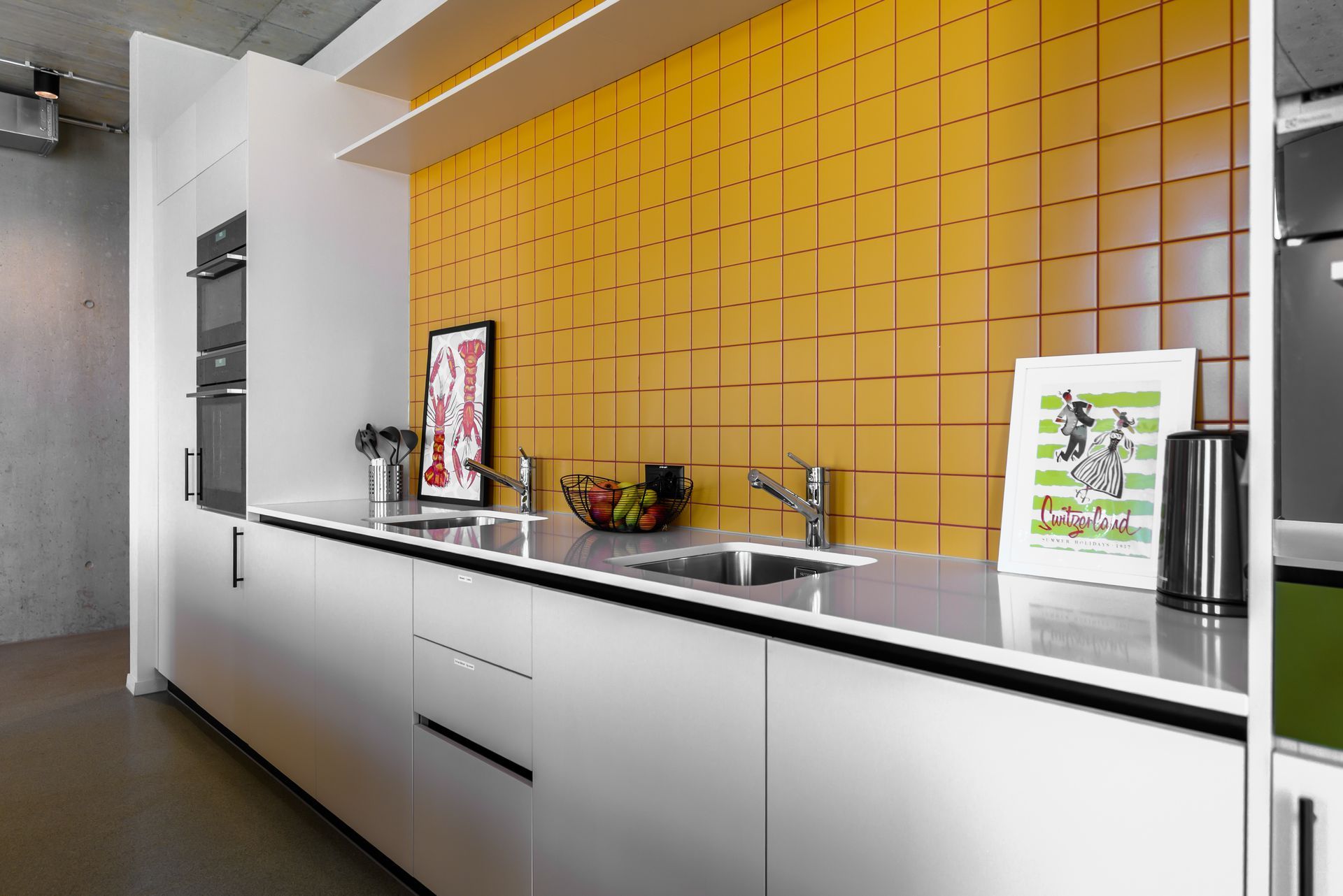A kitchen with white cabinets and yellow tiles on the wall