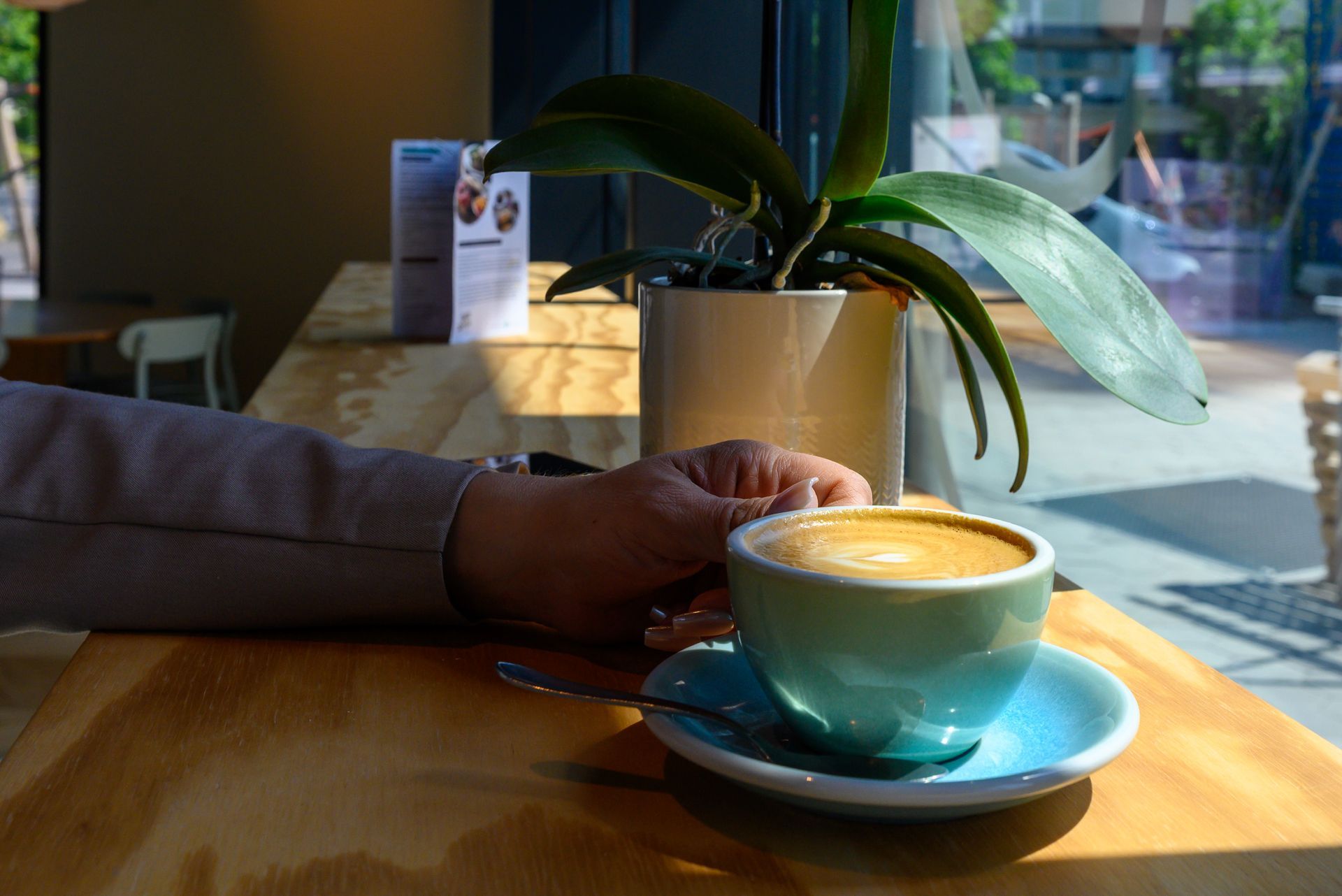 Eine Person sitzt mit einer Tasse Kaffee an einem Tisch.