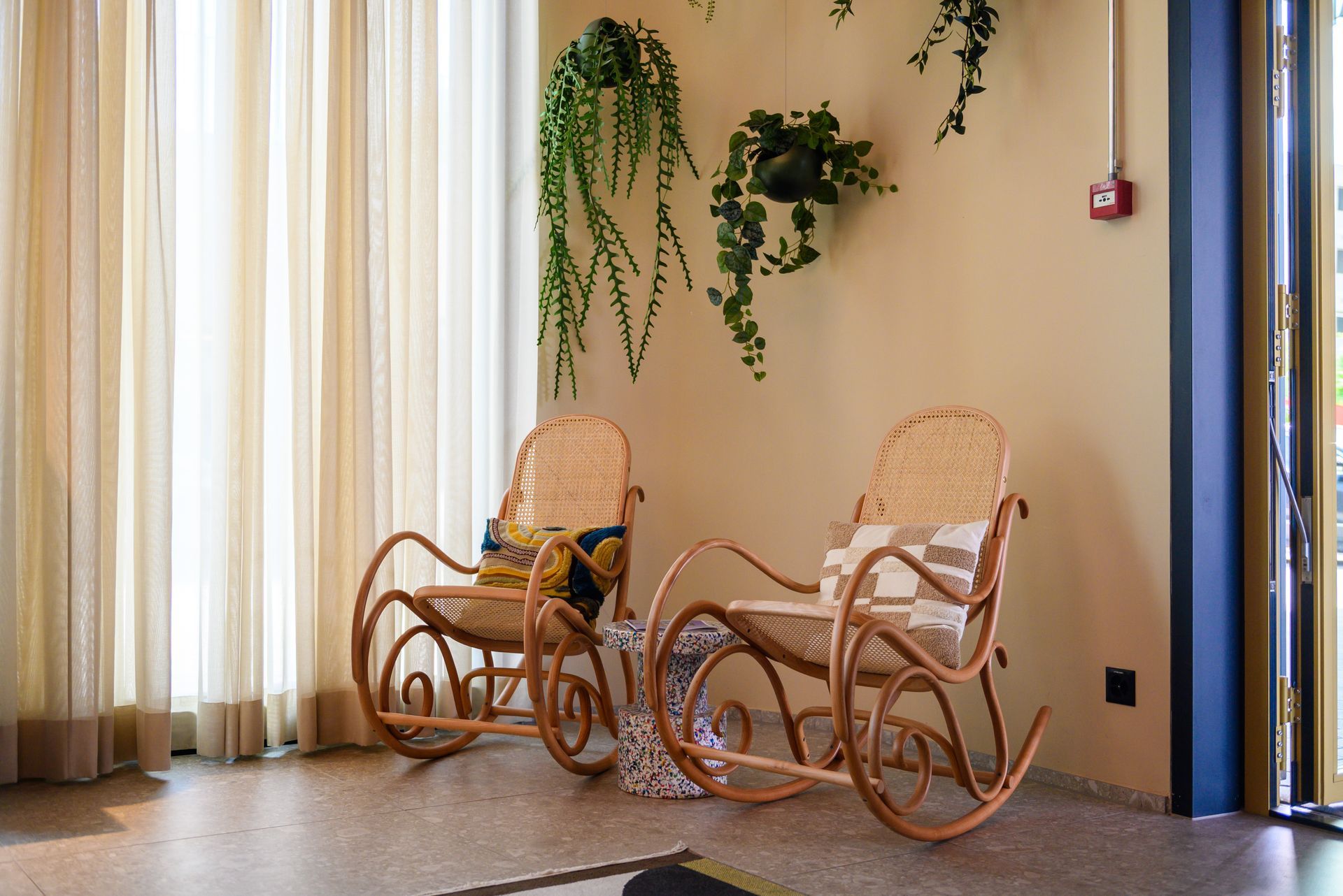 Two rocking chairs are sitting in a room next to a window.