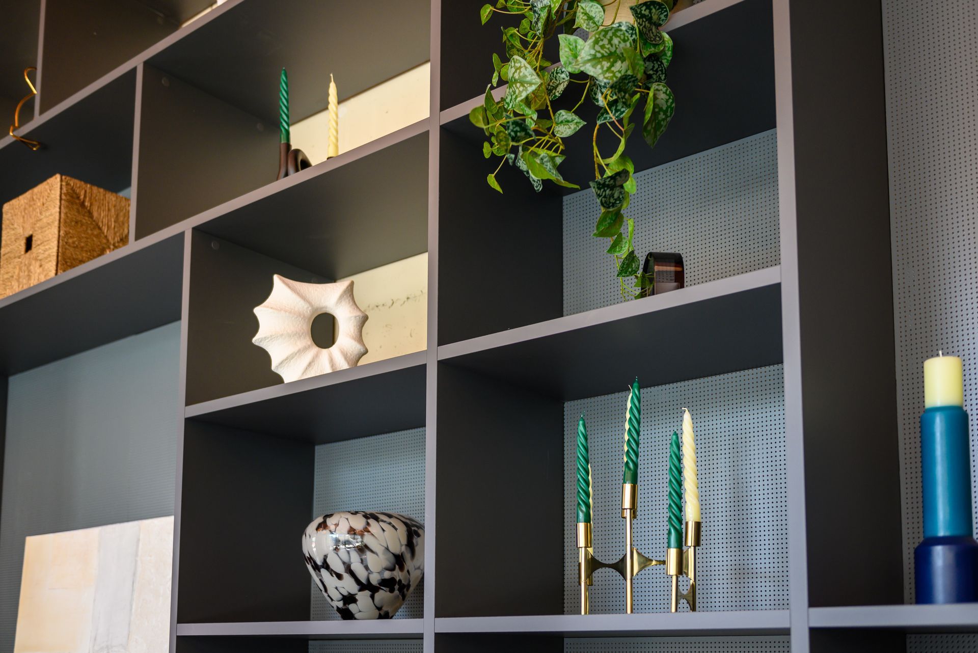 A shelf with candles , vases , and a plant on it.