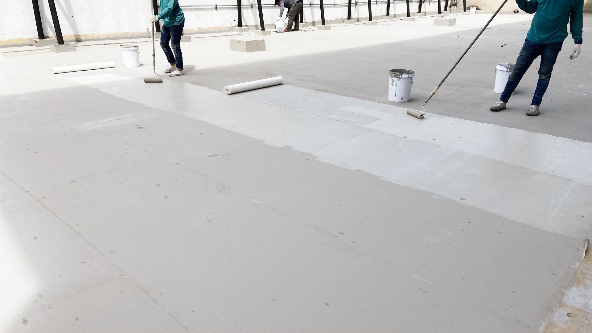 Workers applying liquid waterproofing on the rooftop surface. Workers applying liquid waterproofing on the rooftop surface.