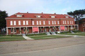 Red brick townhomes with covered porches, white doors, and a red roof.