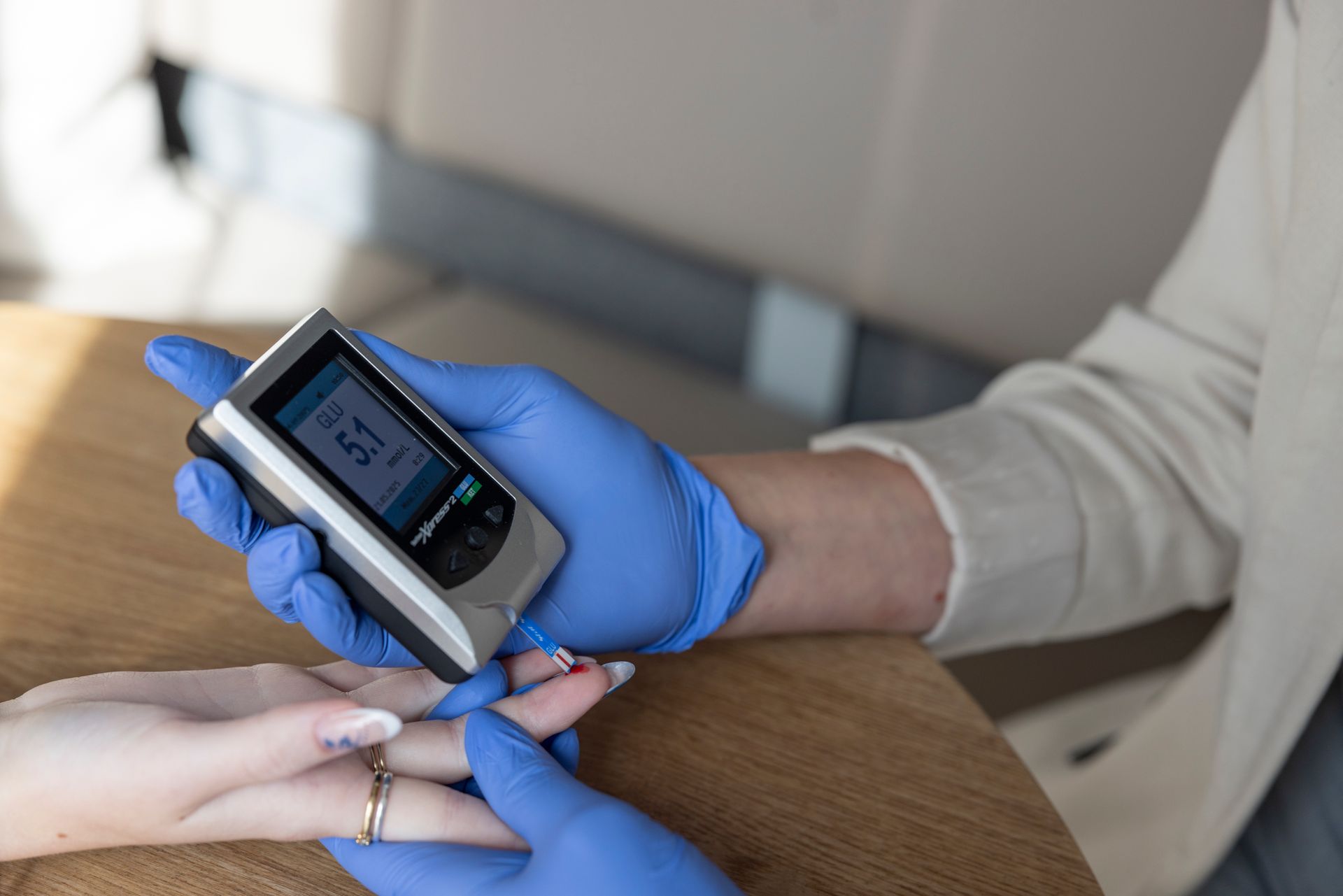 Een persoon met handschoenen aan gebruikt een bloedglucosemeter om de vinger van een andere persoon te meten.