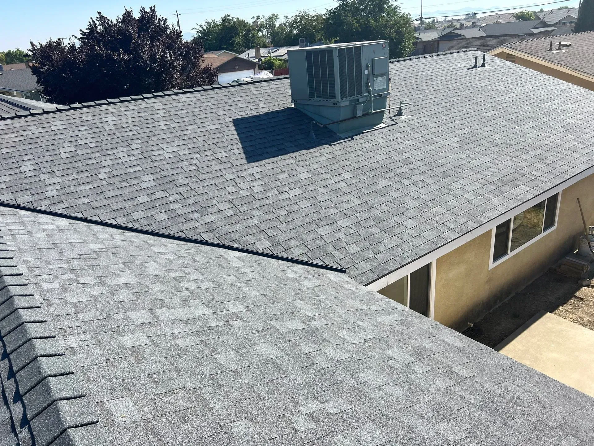 A man is fixing a gutter on a house with a drill.