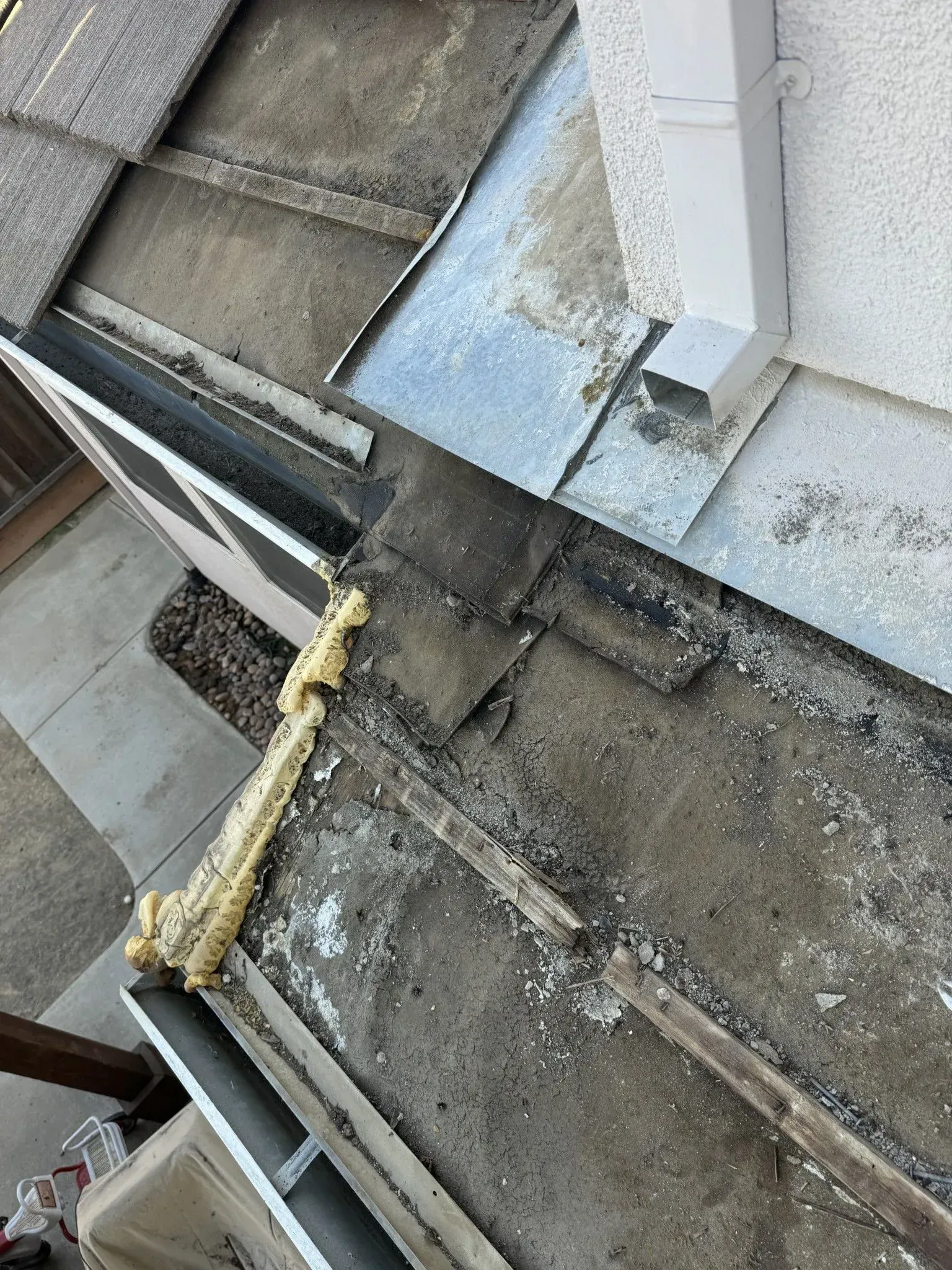 A man is fixing a gutter on a house with a drill.