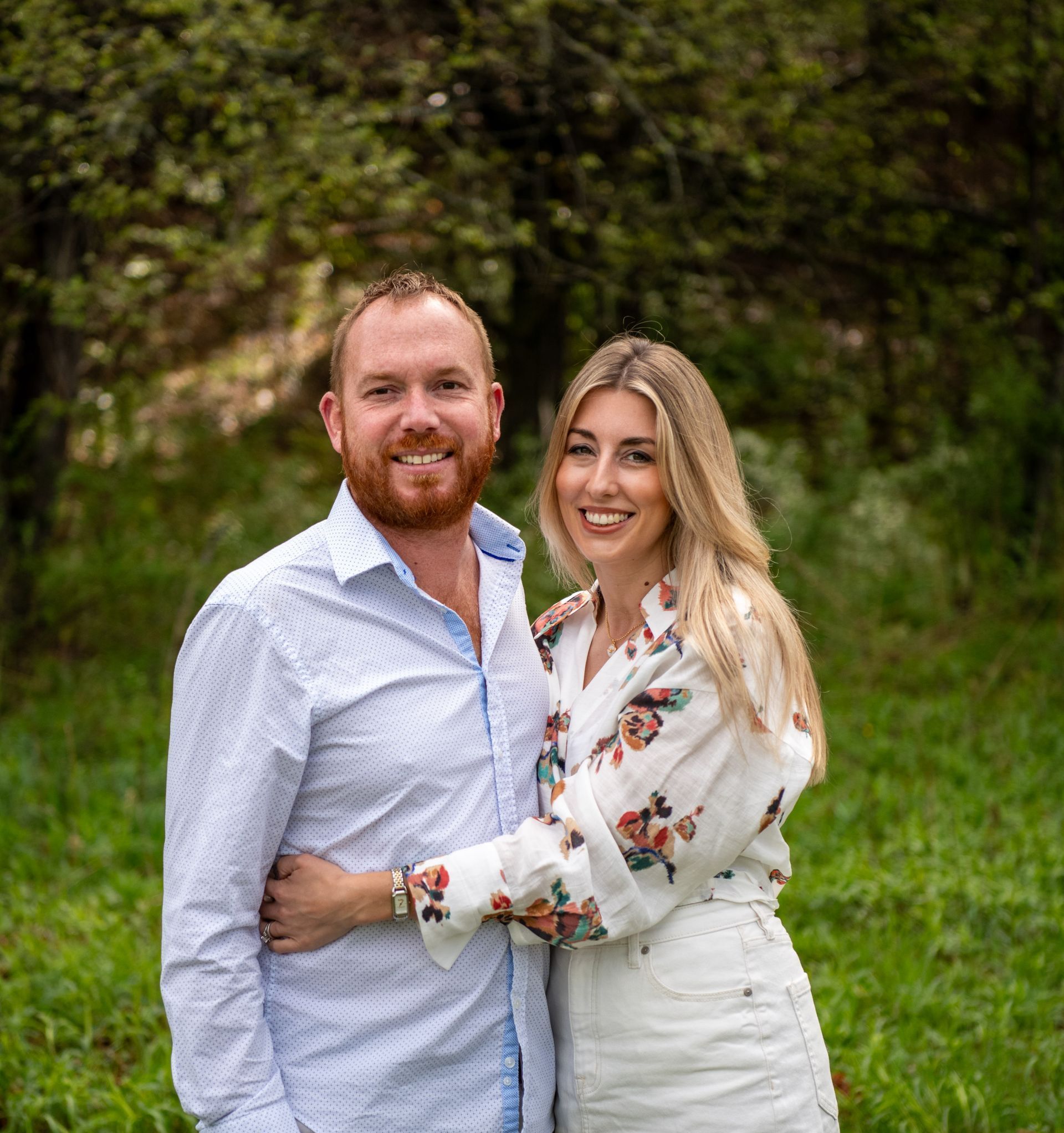 A man and a woman are posing for a picture in a field.