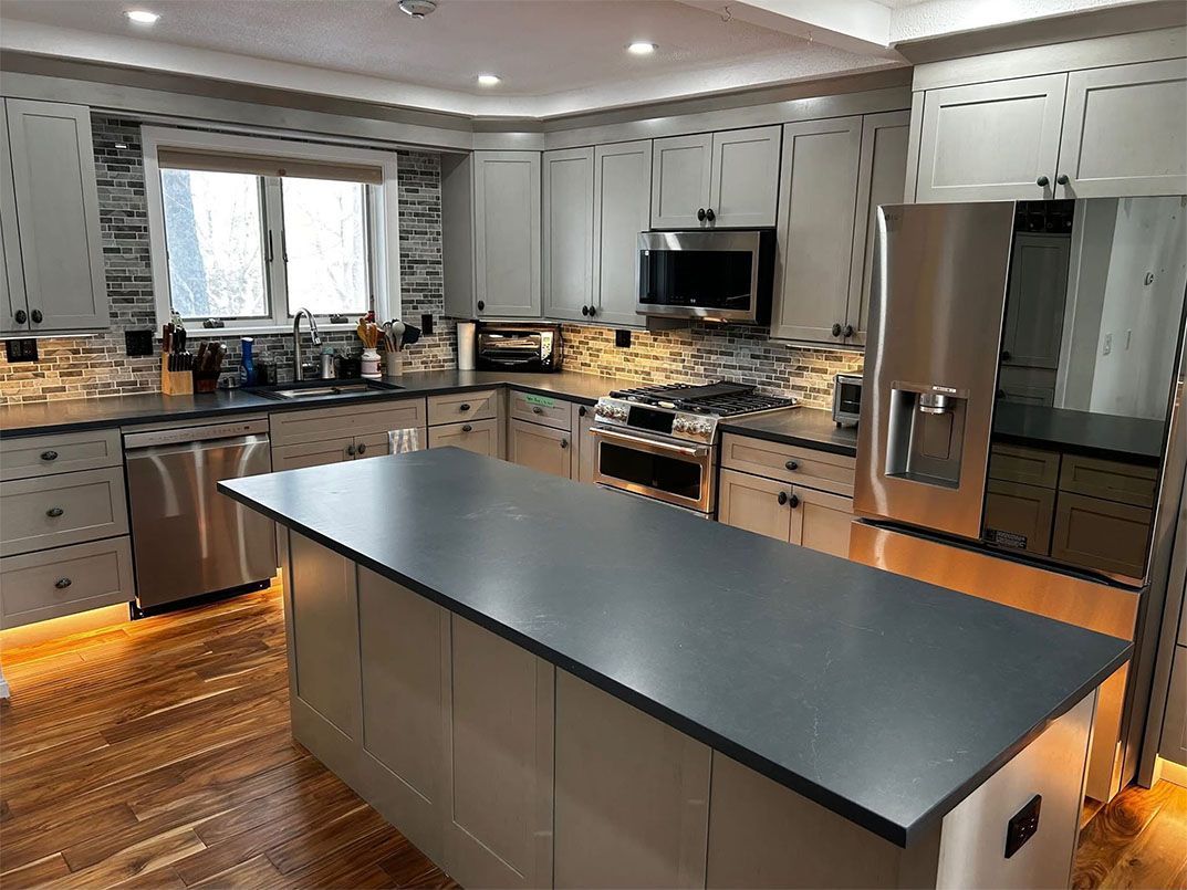 A porch with a wooden ceiling and railing leading to a house.