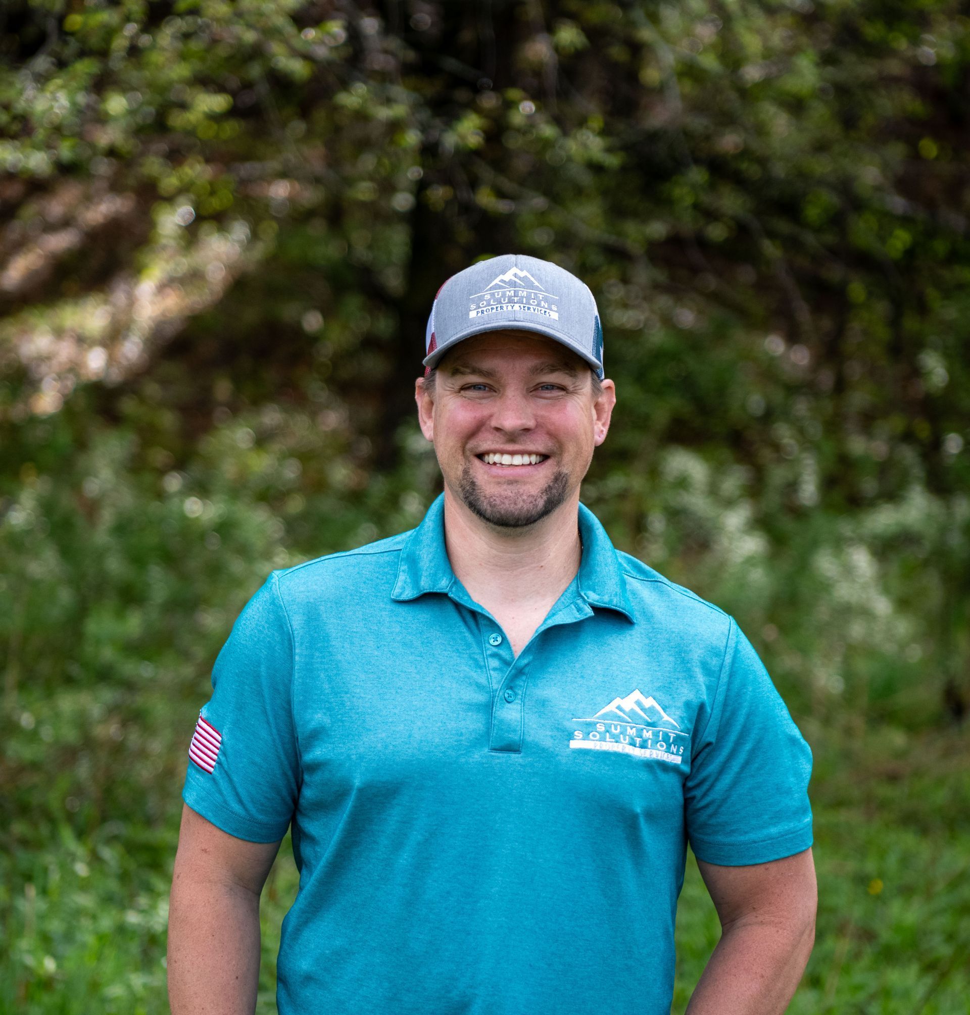 A man wearing a blue polo shirt and a hat is smiling for the camera.