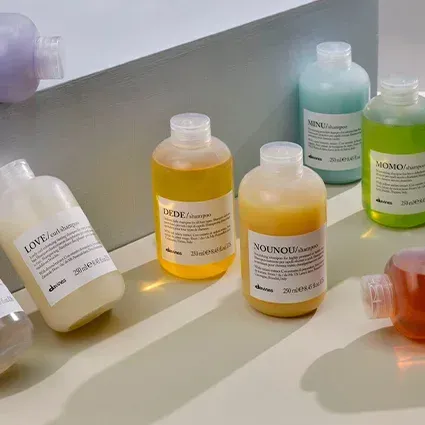 Bottles of shampoo in various colors on a white and light green surface.