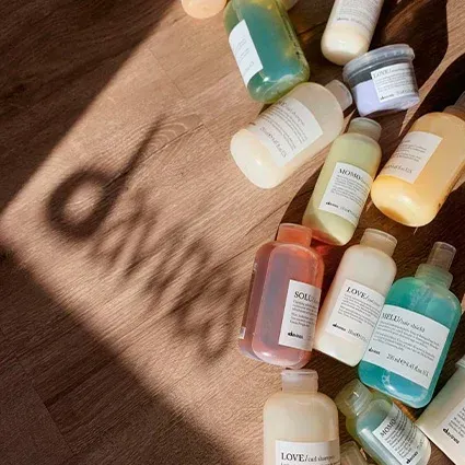 Bottles of hair products scattered on wood, shadow of the word