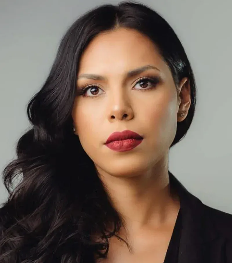 Woman with dark hair and red lipstick, looking directly at the camera.