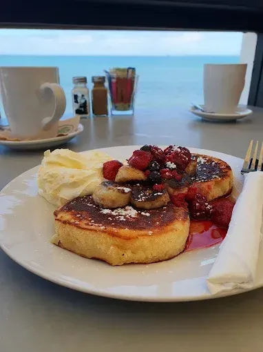 A plate of pancakes with whipped cream and berries on a table.