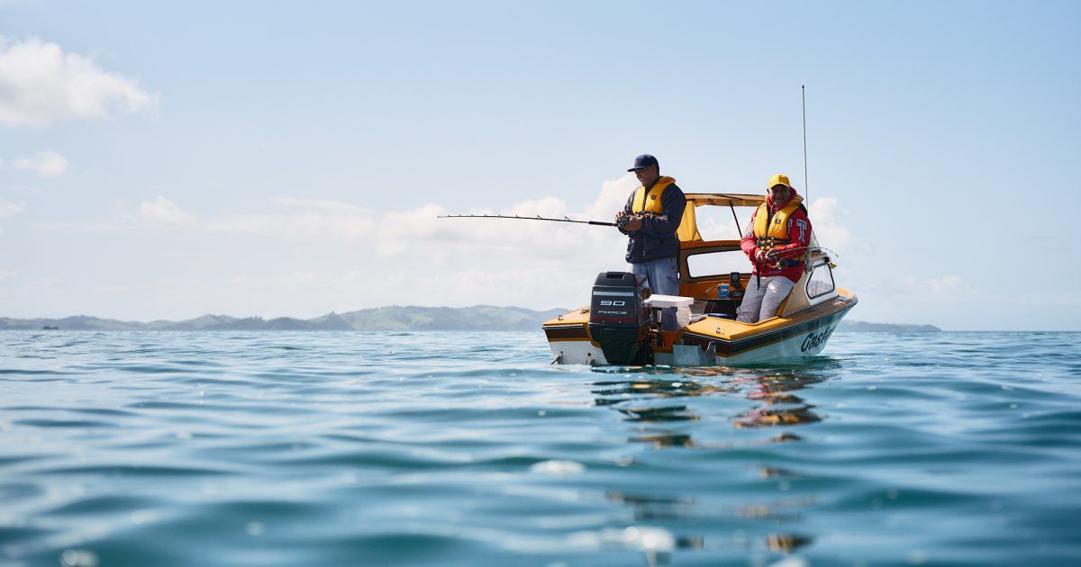 Two people are fishing in a boat in the ocean.