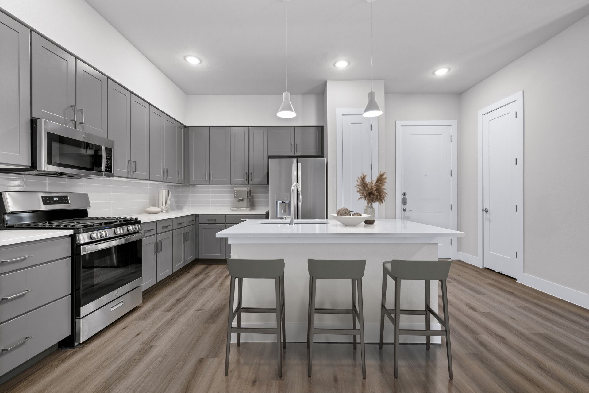 A kitchen with gray cabinets, stainless steel appliances, and a large island at The Wyatt, offers pet-friendly apartments in North Austin, TX.