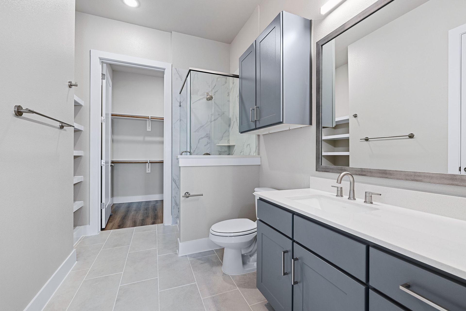 A bathroom with a toilet, sink, mirror, and walk-in closet at The Wyatt, offers luxury apartments in North Austin, TX.