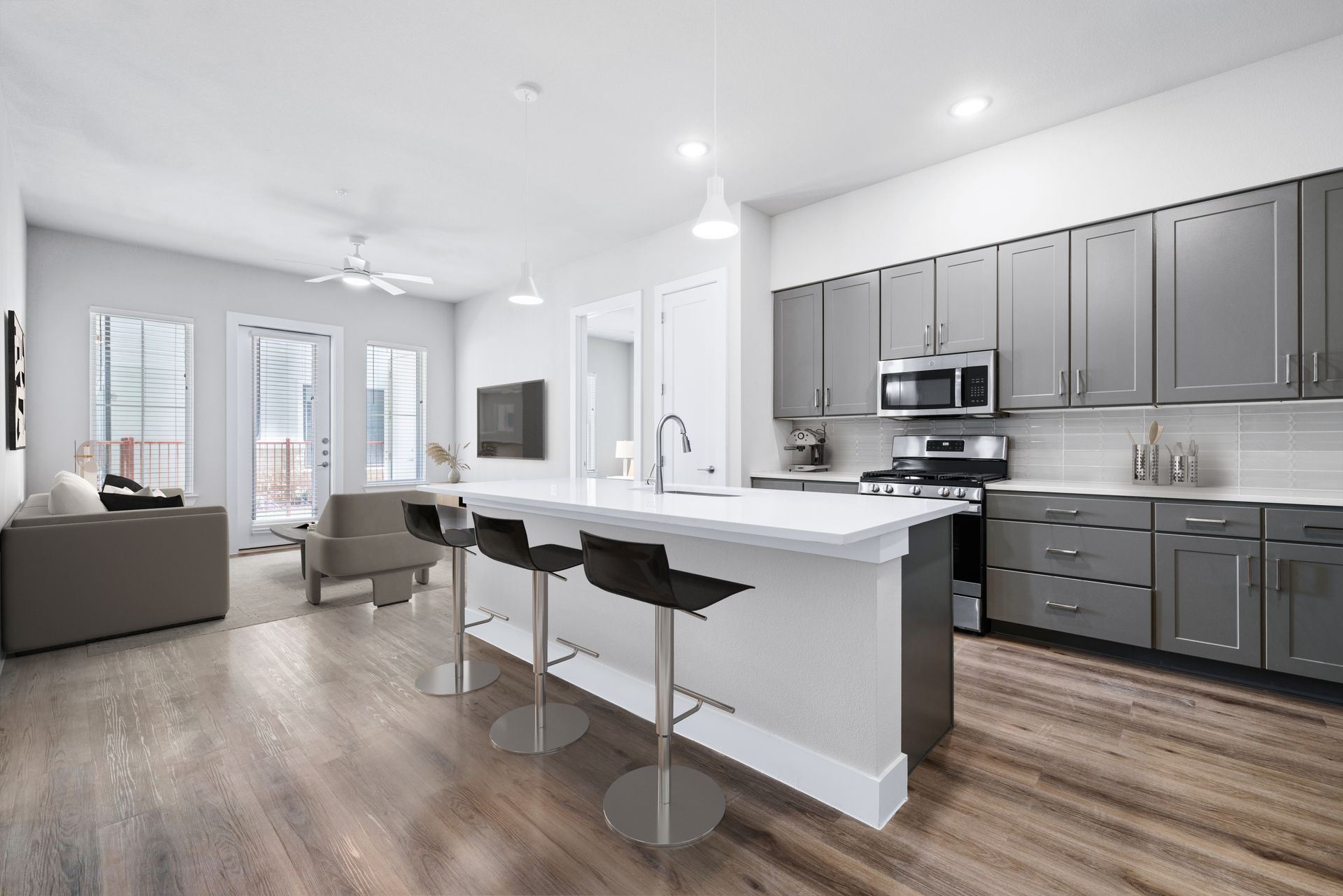 A kitchen with a large island and stools in a living room at The Wyatt, offers luxury apartments in North Austin, TX.