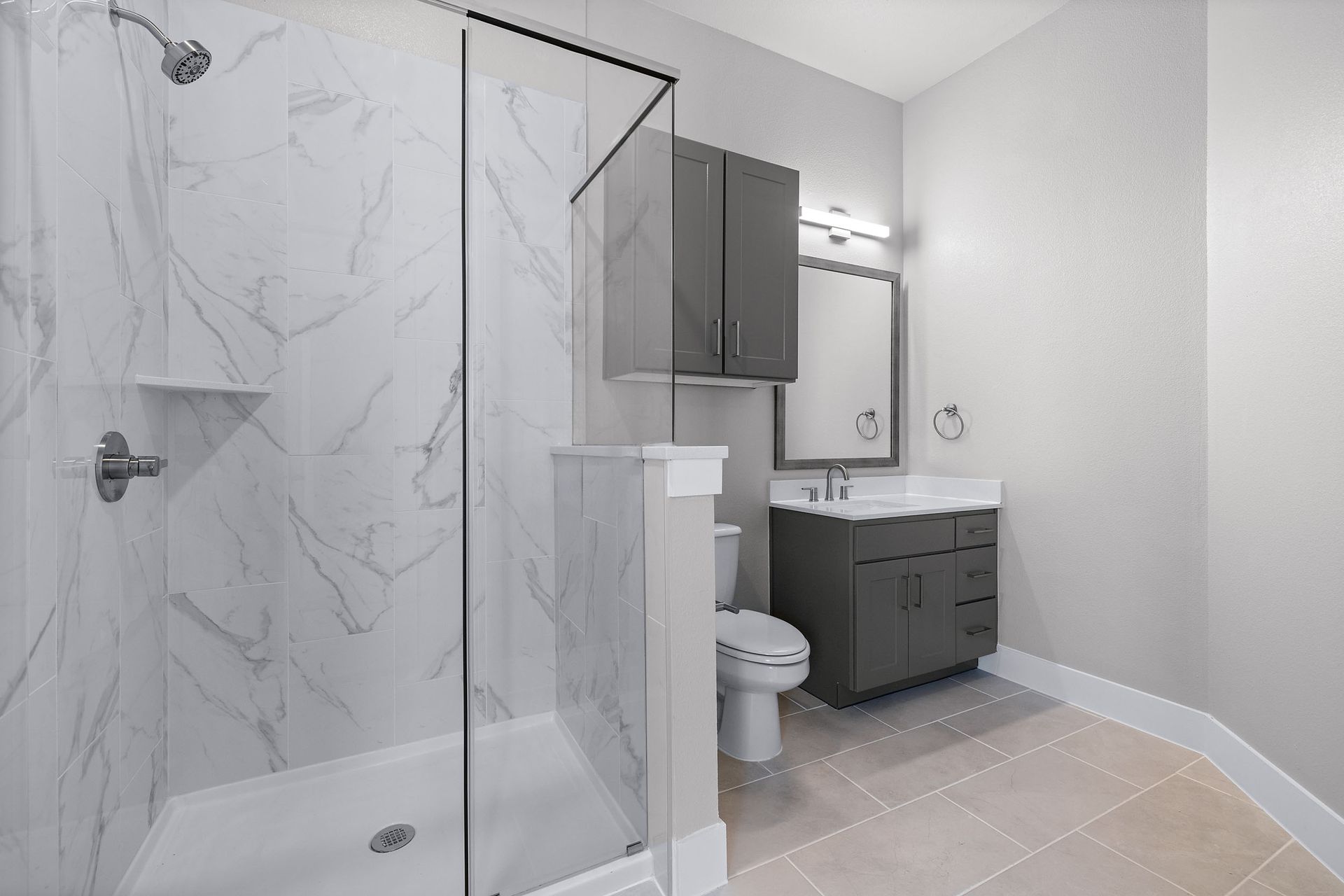 A bathroom with a toilet, sink, glass shower, and mirror at The Wyatt, offers pet-friendly Pearson Ranch apartments in North Austin, TX.